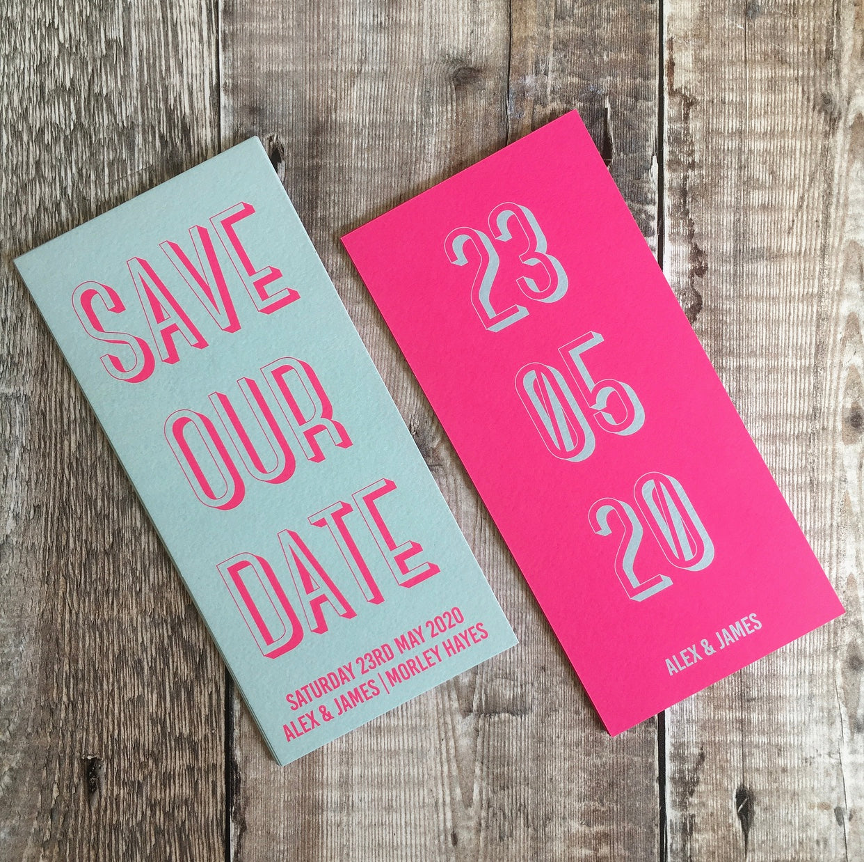 Bookmark-style wedding invitation/save the date. Front and back view. Front (left) has a teal blue background, with fluorescent pink text. Back (right) has a pink fluorescent background, with the date of the wedding in a teal colour. The overall style is typographic and bold.