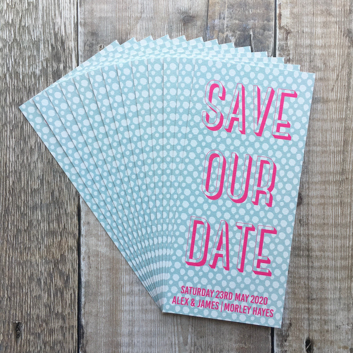 Bookmark-style wedding invitation/save the date. 99mm x 210mm. Pale blue background, with a white spotted pattern. Text is typographic, and written in fluorescent pink.